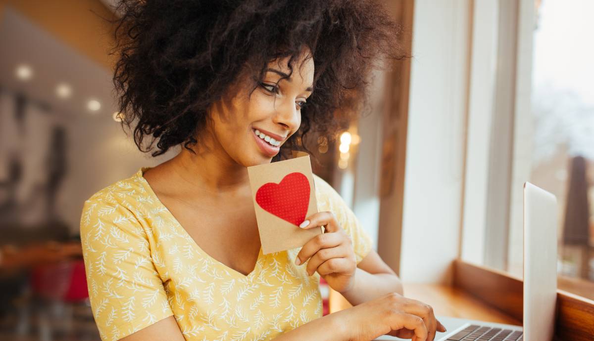 Attractive woman holding a card with a heart on it.