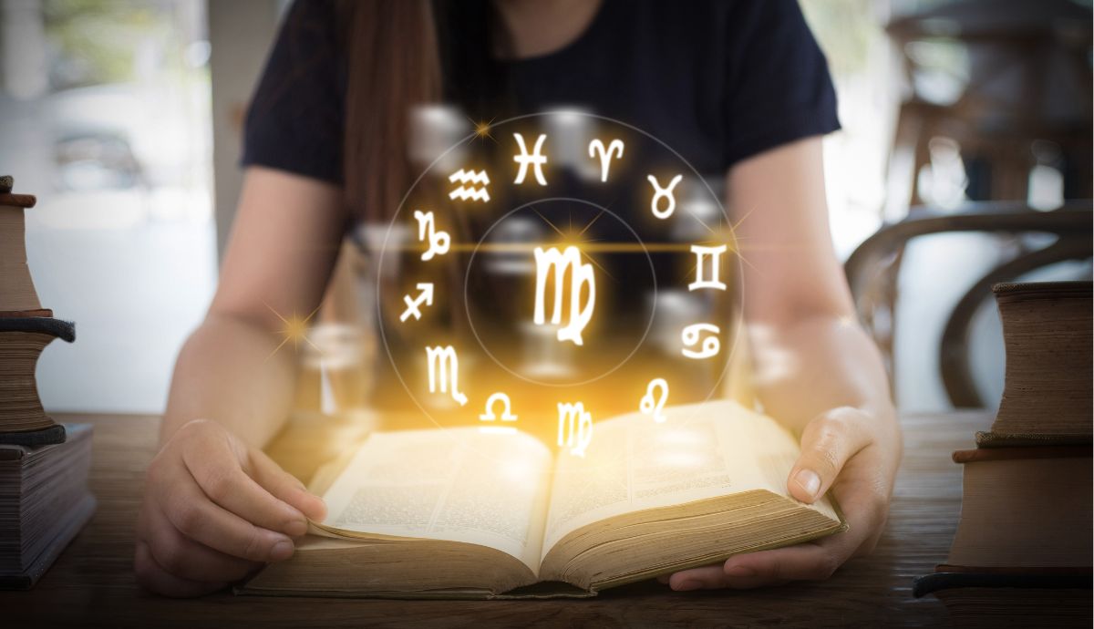 Open book with glowing zodiac symbols emerging from it.