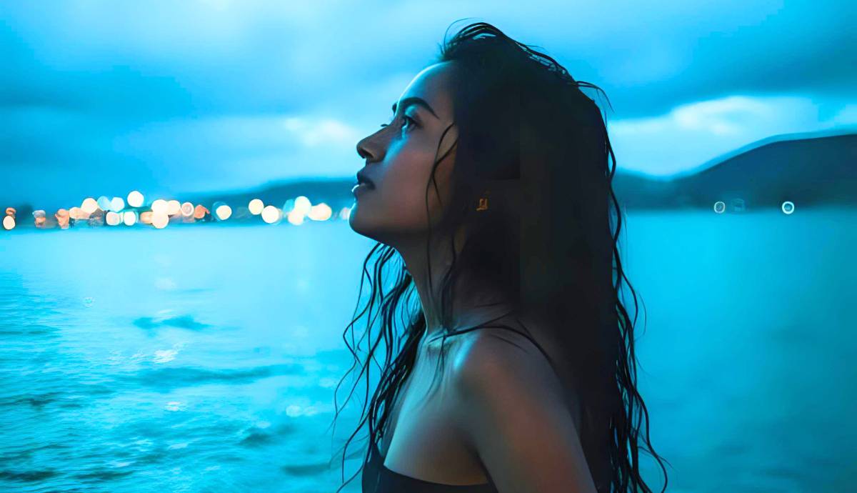 Side profile of young woman looking up towards the sky with a hopeful expression..